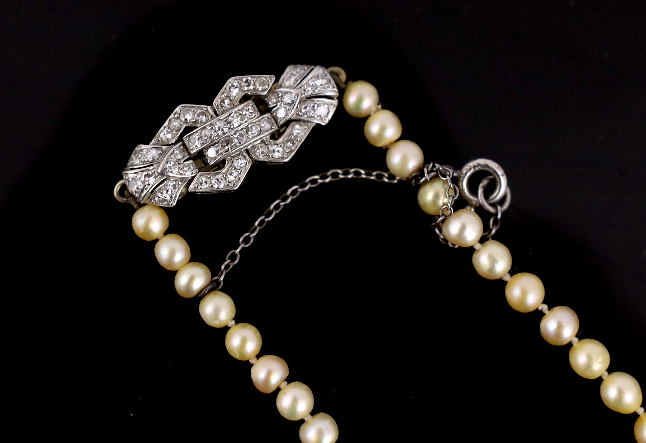 An Edwardian single strand graduated natural saltwater pearl necklace, with gold, platinum and diamond cluster set clasp, with safety chain